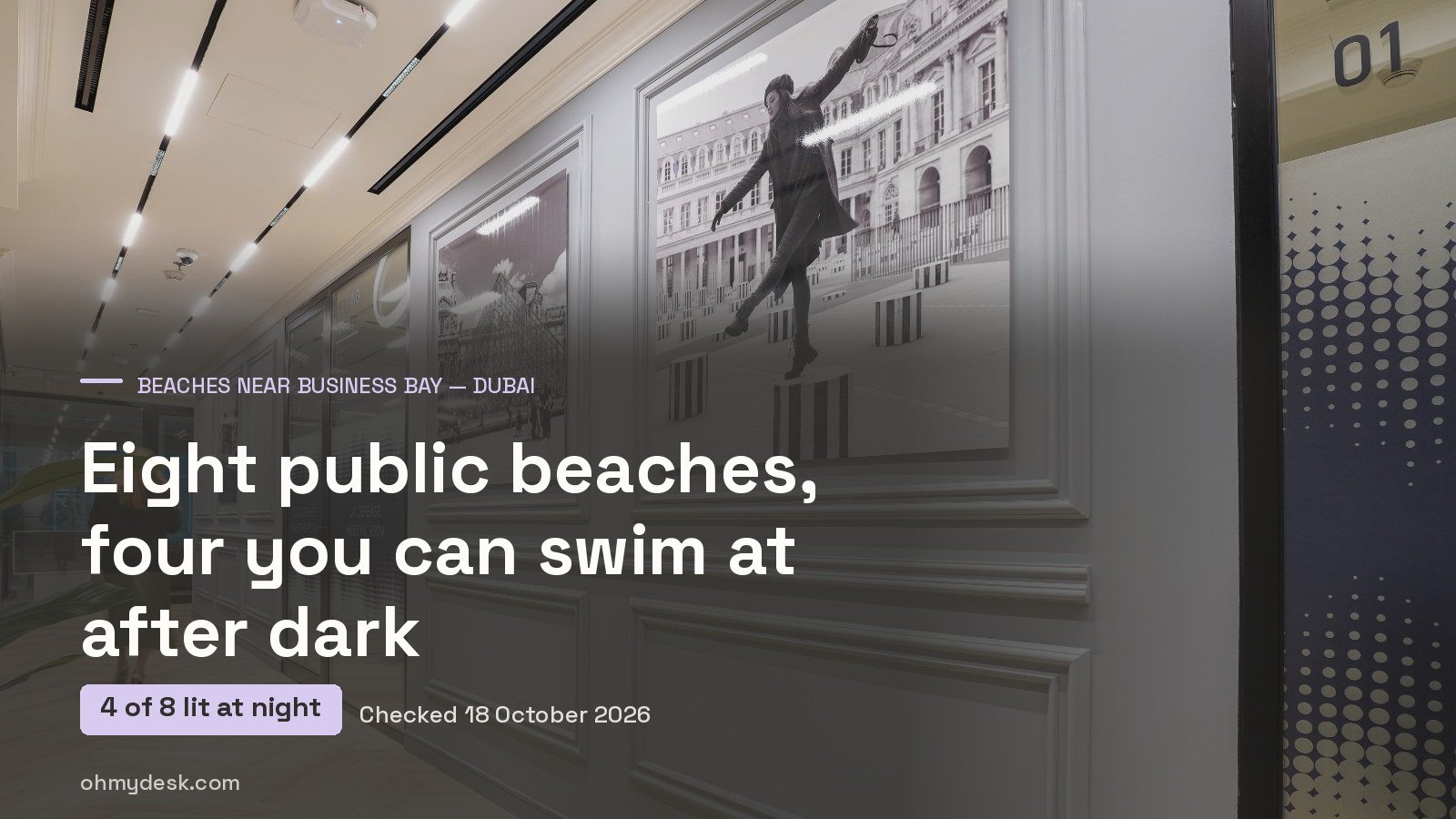 The gallery corridor at Oh My Desk in Business Bay Dubai, framed black-and-white photographs along a panelled wall beside the glass offices, over the title of this guide to the eight Dubai public beaches and the four designated for swimming after dark