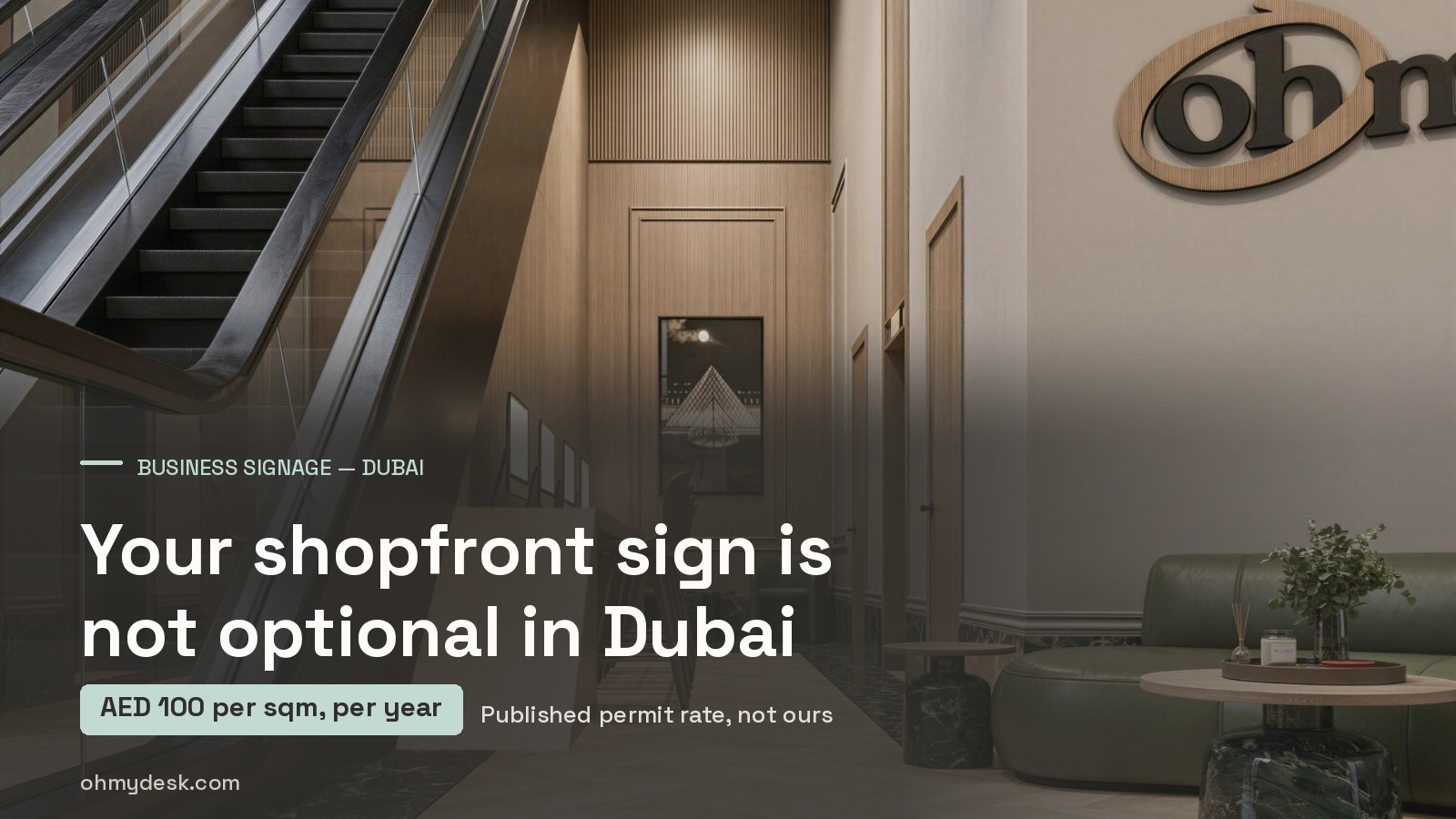 Lobby at Oh My Desk in Dubai Design District, with the escalator, the wood-panelled wall and the dimensional Oh My Desk wall sign mounted above the seating area