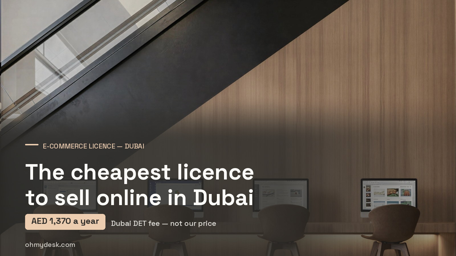 Four screens showing web pages on a lit wooden counter at Oh My Desk Downtown Dubai, under a headline on the AED 1,370 published cost of a Dubai e-commerce licence in 2026