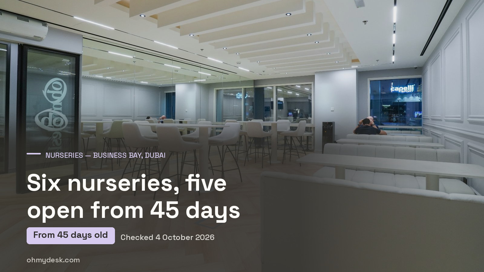 Coworking lounge at Oh My Desk Business Bay on Marasi Drive, with high shared tables, a glazed meeting room and a curved lounge seat, the desk a parent returns to after drop-off
