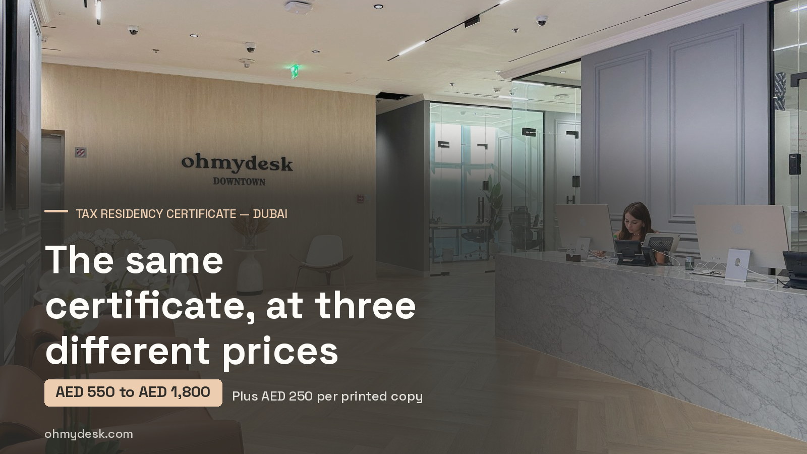 Open-plan workspace at Oh My Desk Downtown Dubai, with a glazed meeting room and a row of fitted desks behind a curved lounge seat, seen from the lounge a company would move into