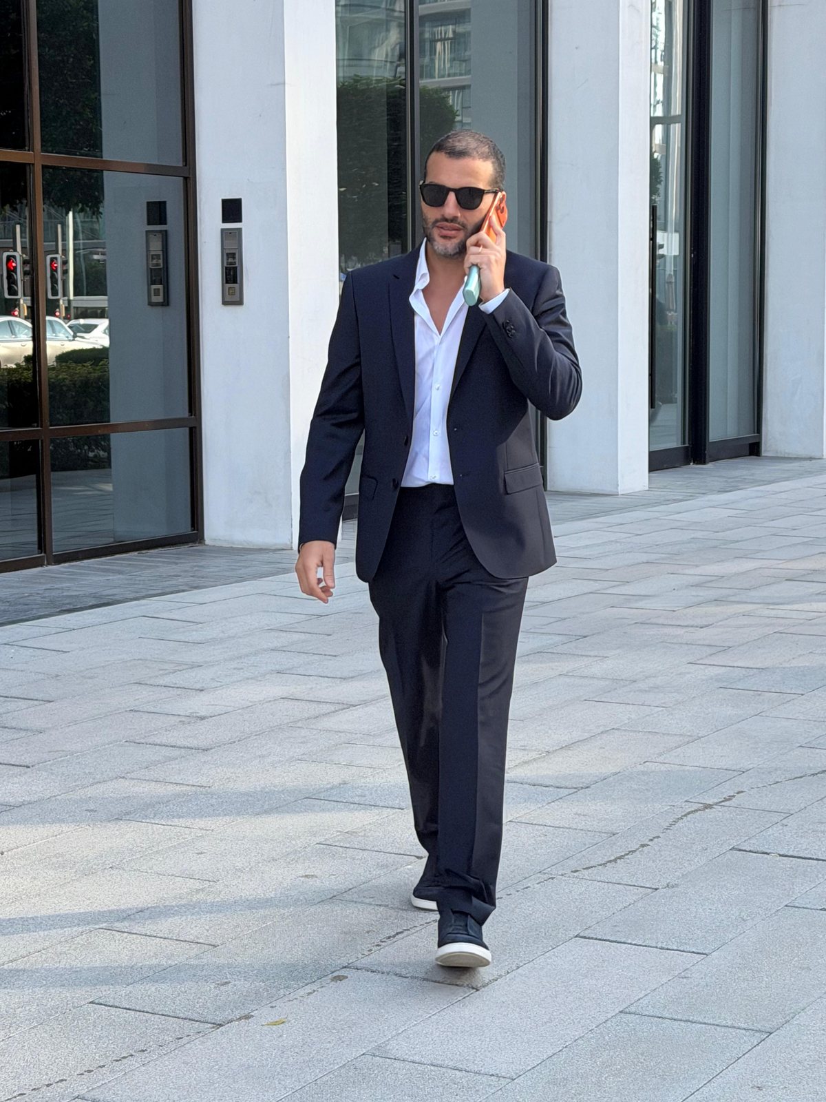 Guillaume Rassemi in a navy suit walking in Dubai, on the phone