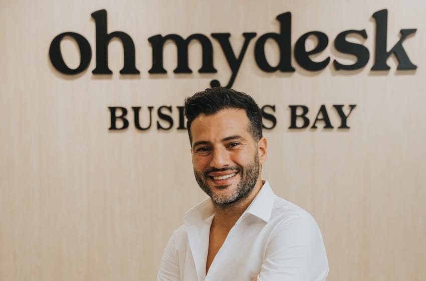 Guillaume Rassemi smiling in front of the Oh My Desk Business Bay sign